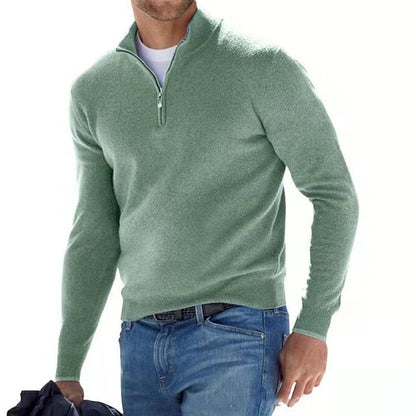 Model walking in the jumper in sage green with a half zip, worn over a white tee and blue jeans. 2