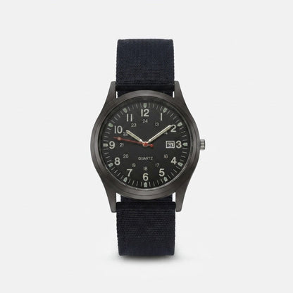 Second front view of the black-dialled watch with luminous hands, red seconds hand and black nylon strap on a light background. 9