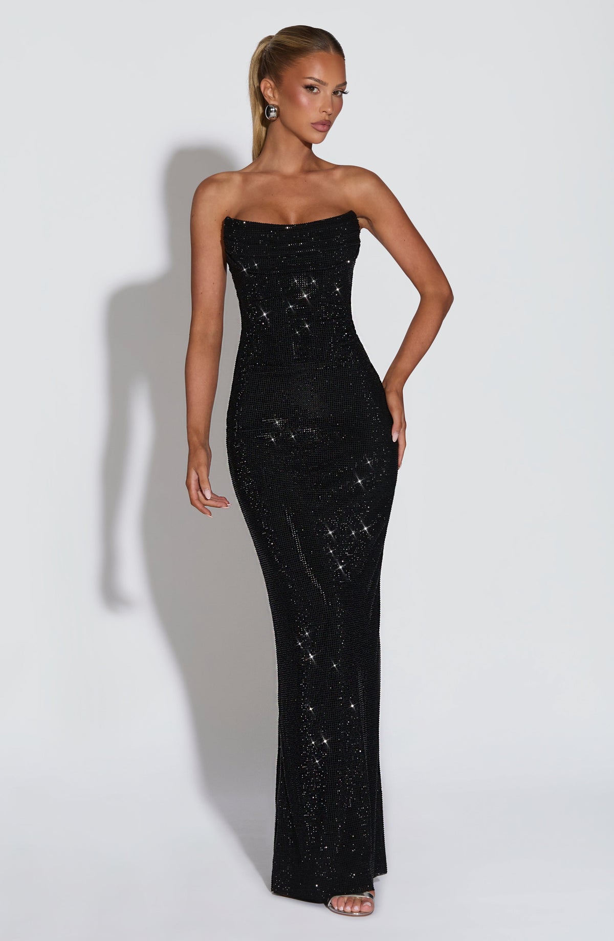 Model wearing the black sparkling strapless maxi dress, front view, one hand on her hip 22