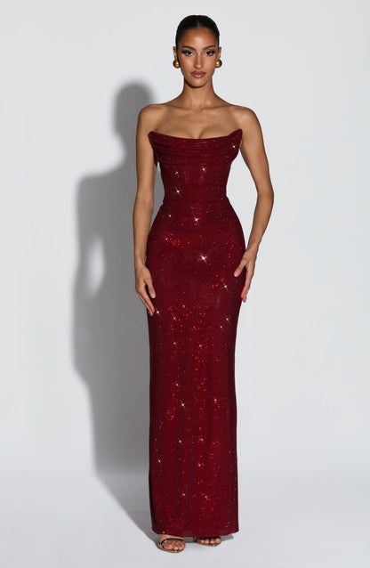 Model faces front in the burgundy rhinestone maxi dress, strapless draped neckline, gold earrings and heels 1