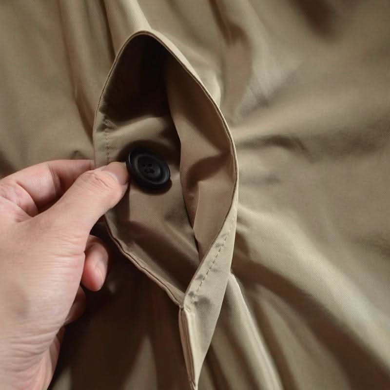 Close-up of a hand holding open a beige coat's inner pocket, showing a black button 8