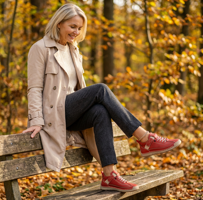 Woman on a wooden bench with one leg raised, showing red lace-up trainers with a strap 23