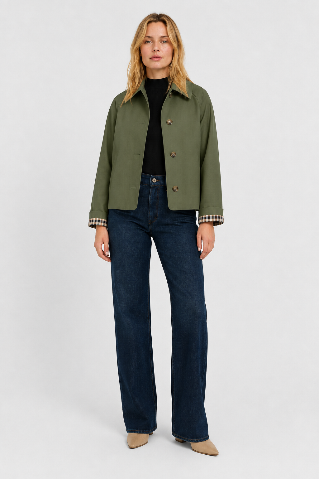 Full-length front view of the olive green jacket worn with a black top, dark wide-leg jeans and beige boots. 10
