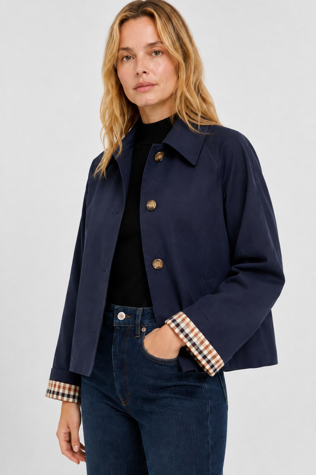 Navy jacket in three-quarter view with hand in jeans pocket, showing the collar, horn-style buttons and gingham cuffs. 14