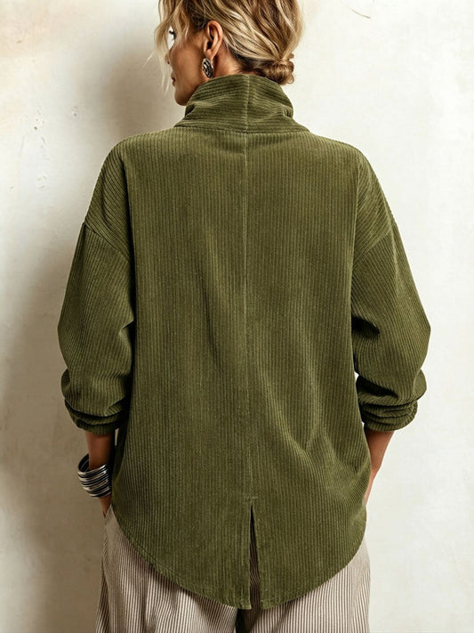 Back view of the olive green corduroy sweater on a model, showing the high collar, drop shoulders and centre slit in the curved hem. 2