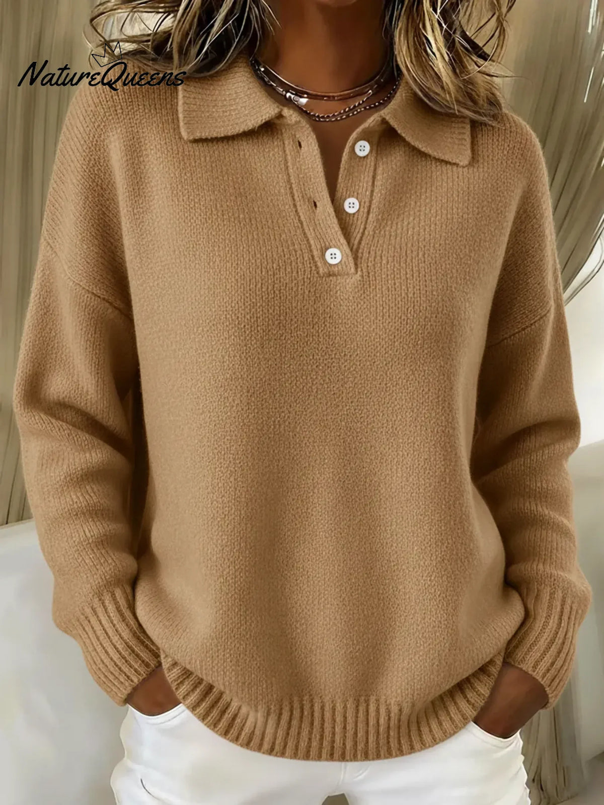 Model wearing the knitted polo sweater in camel tan, worn with white trousers, showing the ribbed hem and cuffs. 4