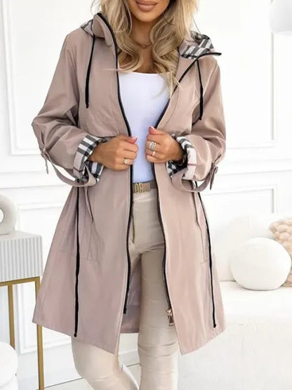 Model in the beige hooded jacket worn open with a white top and beige trousers, showing zip, drawcords and checked cuff lining. 2