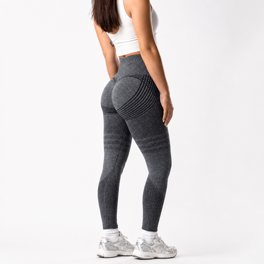 Rear three-quarter view of dark grey leggings with curved stripes across the seat and mesh thigh detail, worn with a white crop top. 23