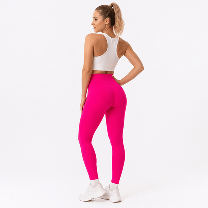 Rear view of bright pink leggings with a high waistband, worn with a white racerback sports bra and trainers. 10