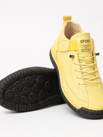 Yellow trainers with a black sole and orange stitching, one tilted to show the studded tread 18