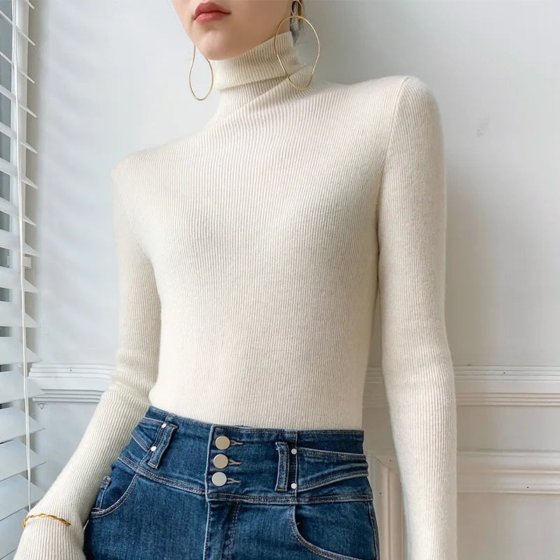 Model wears the ribbed turtleneck jumper in off-white, tucked into high-waisted blue denim 4