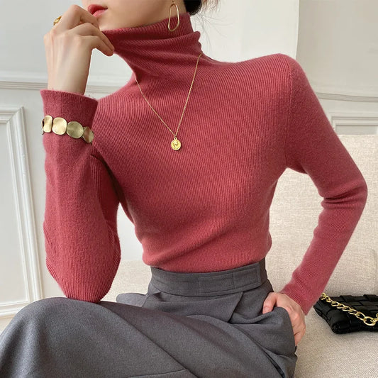 Model wears the slim-fitting ribbed turtleneck jumper in rose red with a grey skirt 2