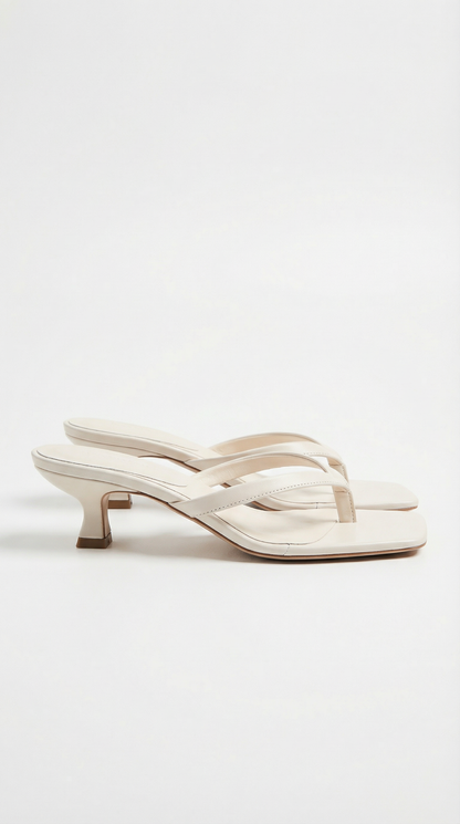 Pair of cream kitten-heel thong sandals with square toes and slim straps, shown from the side on white. 10