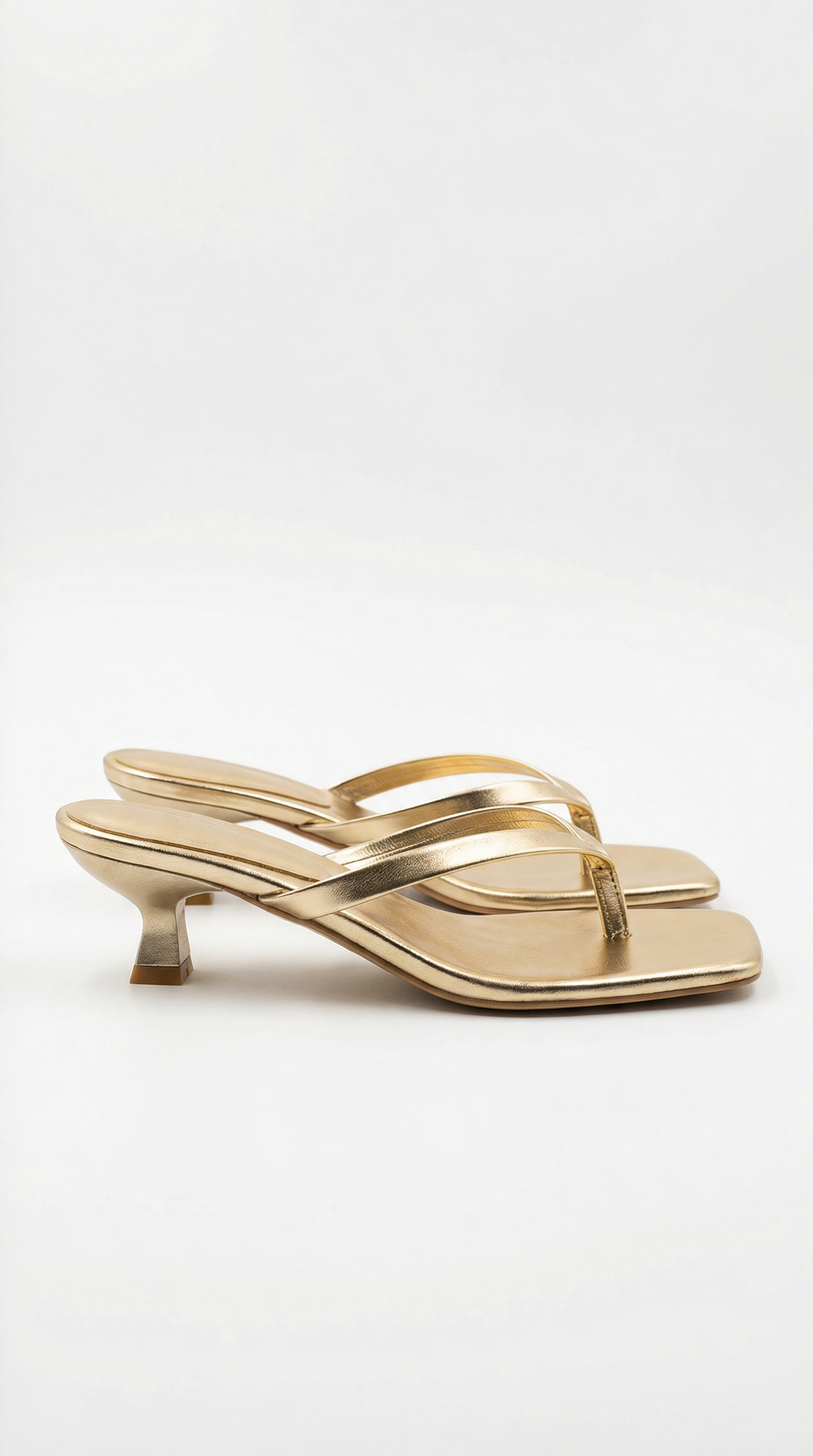 Pair of metallic gold kitten-heel thong sandals with square toes, shown from the side on a plain background. 4