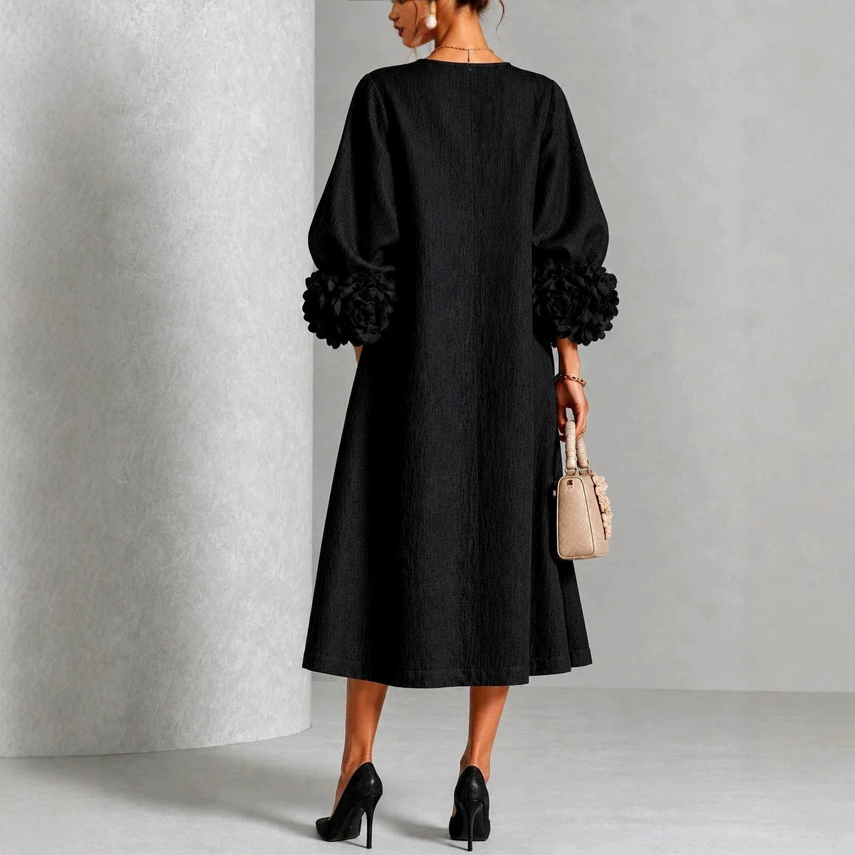 Back view on a model of the black dress, showing the plain back, A-line flare and rose cuffs. 7