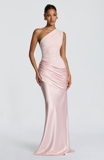 Angled view of the white one-shoulder dress, one hand touching the draped hip, satin skirt flowing to the floor. 27