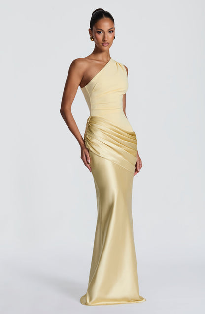 Three-quarter side view of the pale yellow maxi dress, with a fitted bodice, ruched hip detail and fluted satin hem. 47