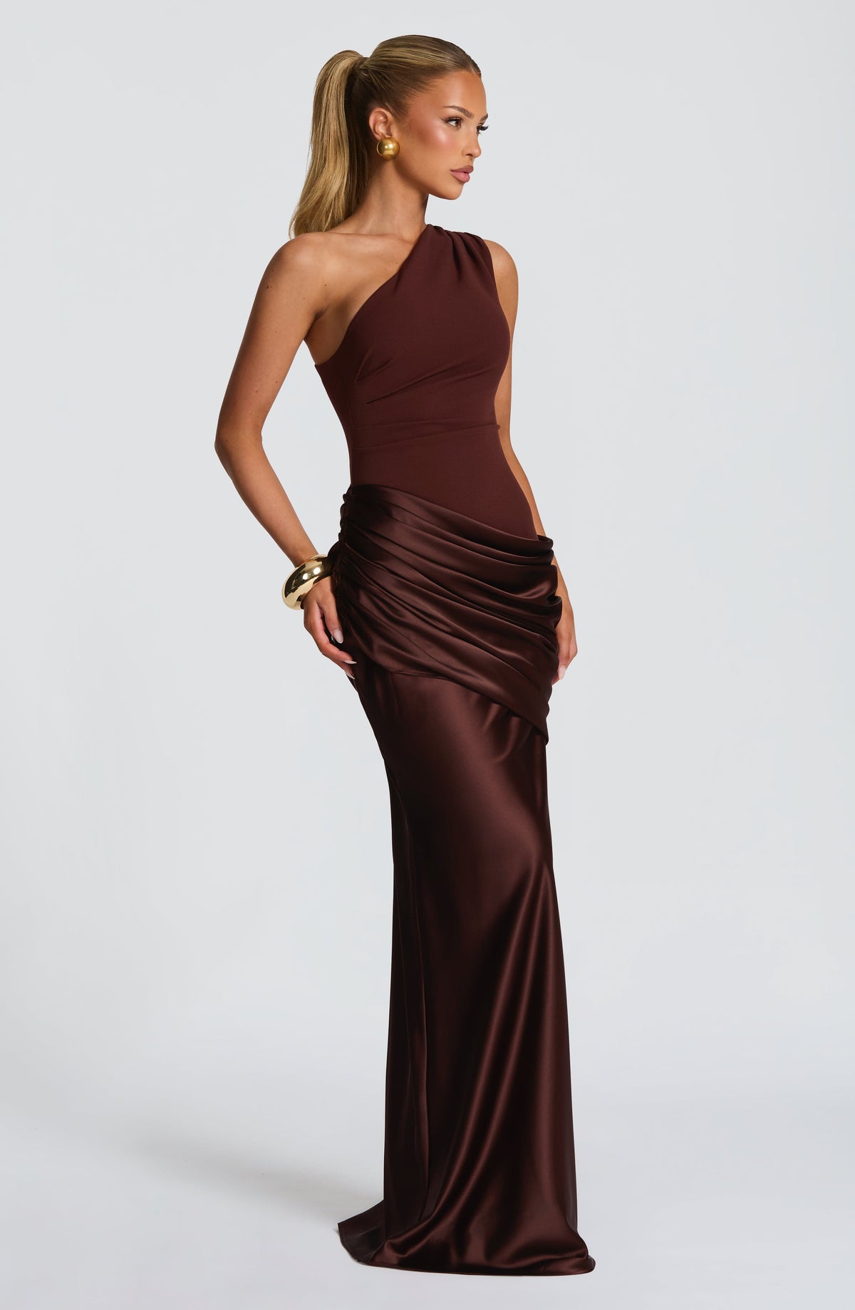 Side-angle view of the brown satin maxi dress, showing the fitted bodice, draped hip and flared floor-length skirt. 12