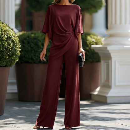 Model photographed from the neck down in the set in deep burgundy, showing the blouse drape and full-length wide-leg trousers. 9
