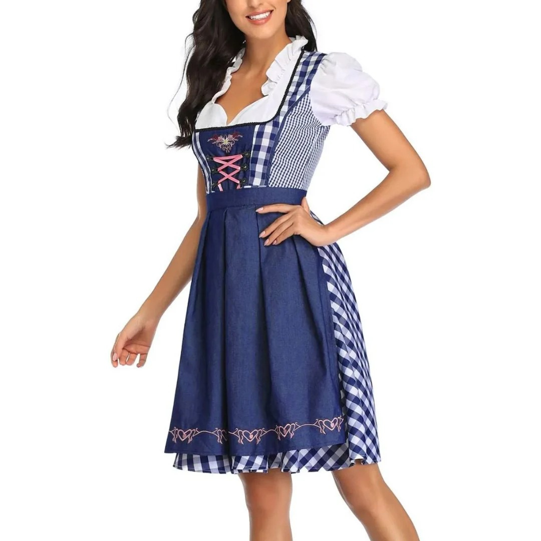 Three-quarter view of the navy and white check dirndl with navy apron and pink bodice lacing, one hand on hip. 6