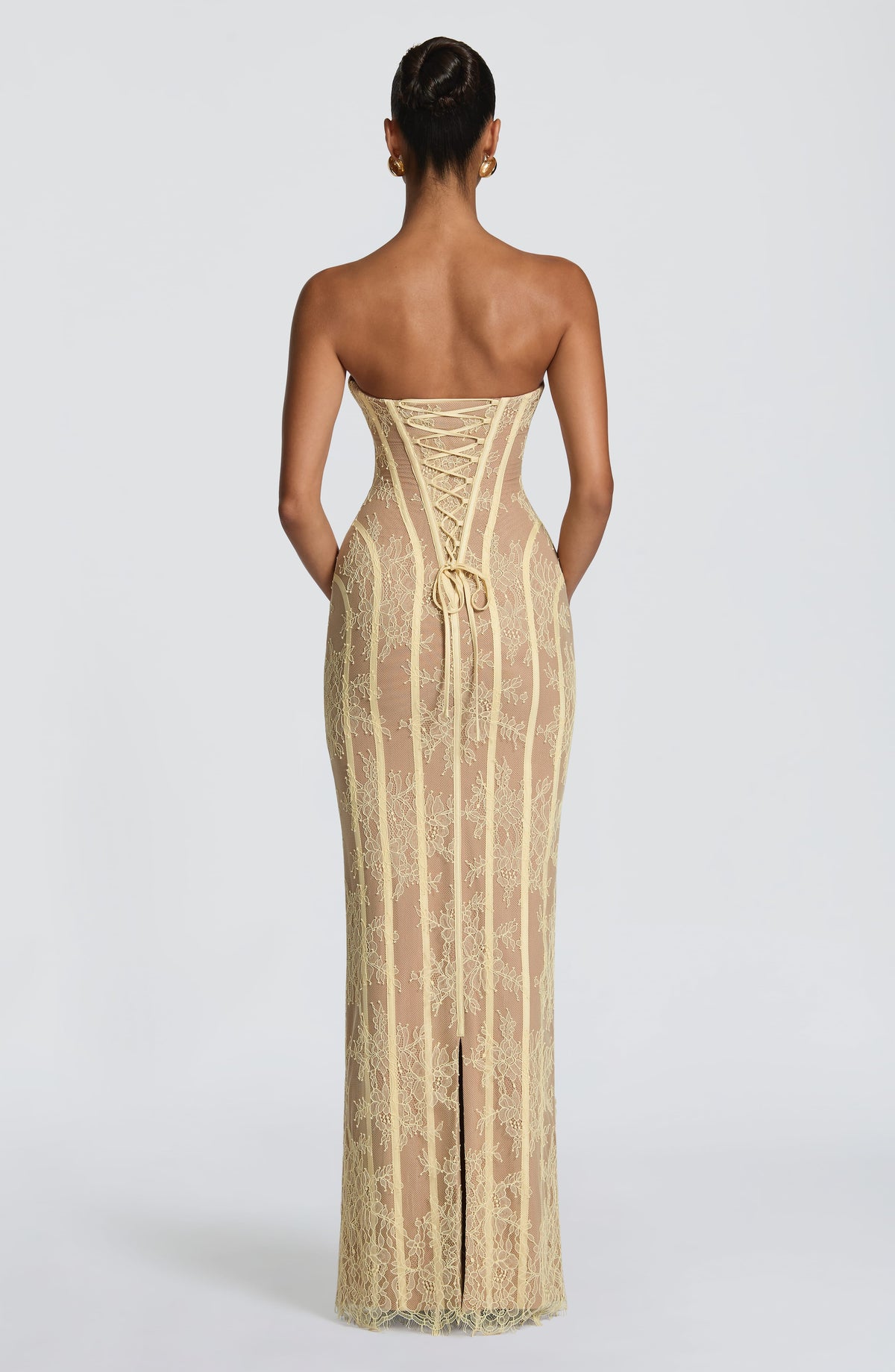 Back view of the pale yellow lace dress, showing the lace-up corset back, a tied bow and the centre slit at the hem. 18