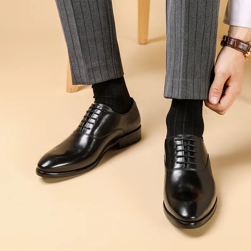 Model in grey pinstripe trousers adjusting a trouser leg while wearing glossy black lace-up Oxfords 1