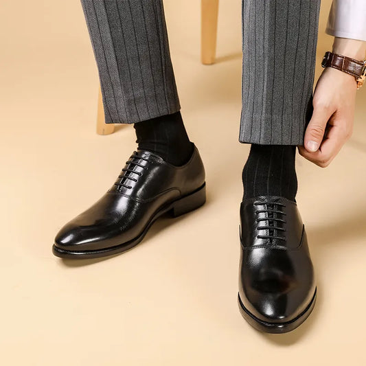 Model in grey pinstripe trousers adjusting a trouser leg while wearing glossy black lace-up Oxfords 1