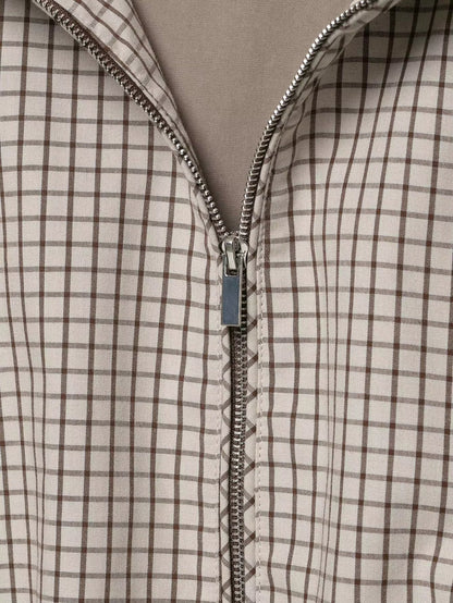 Close-up of the silver zip pull and teeth running down the checked front, with the lining visible at the opening. 6