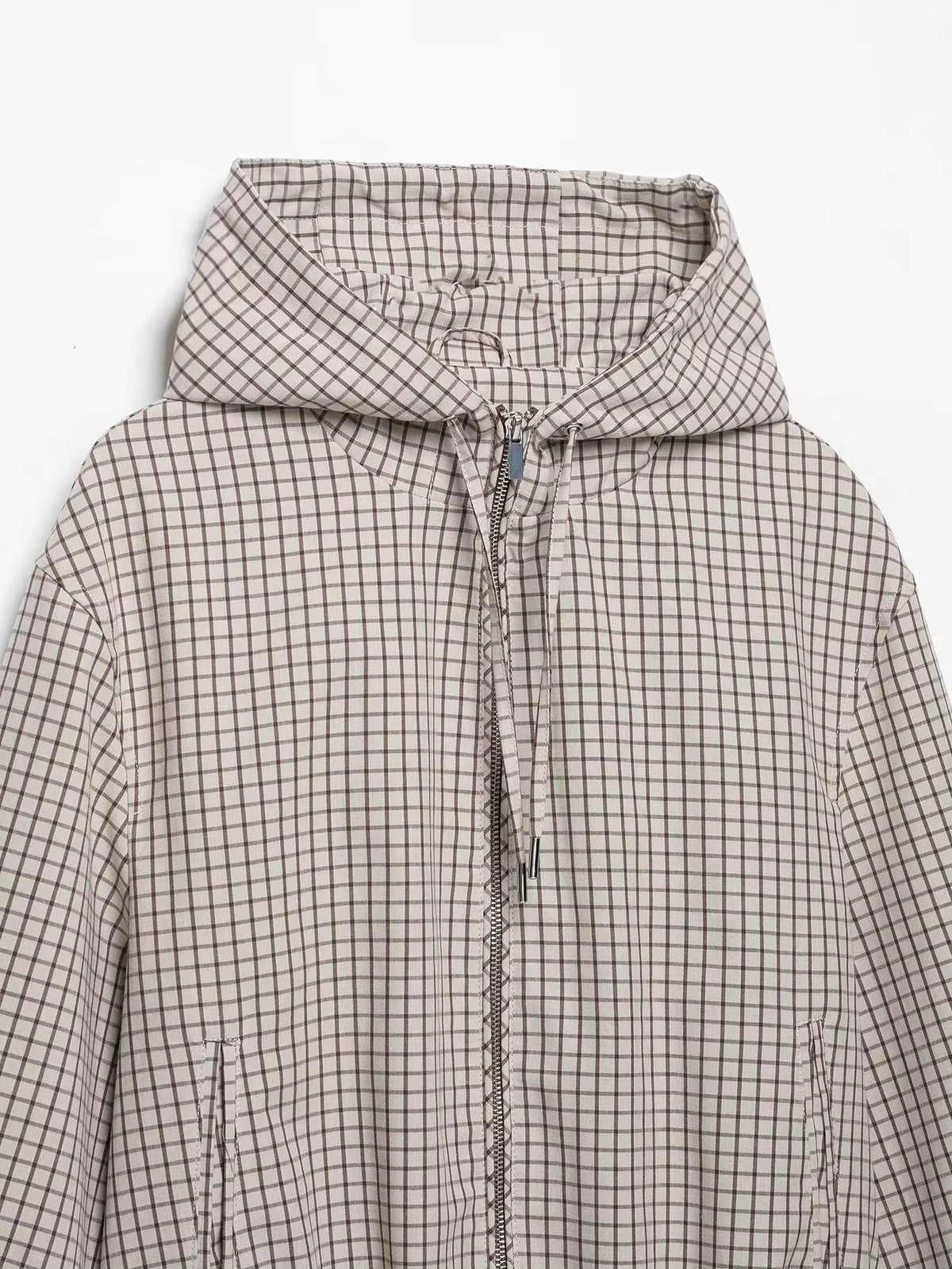 Flat lay of the jacket's upper half, showing the hood, zip, drawstring toggles and slanted side pockets. 7