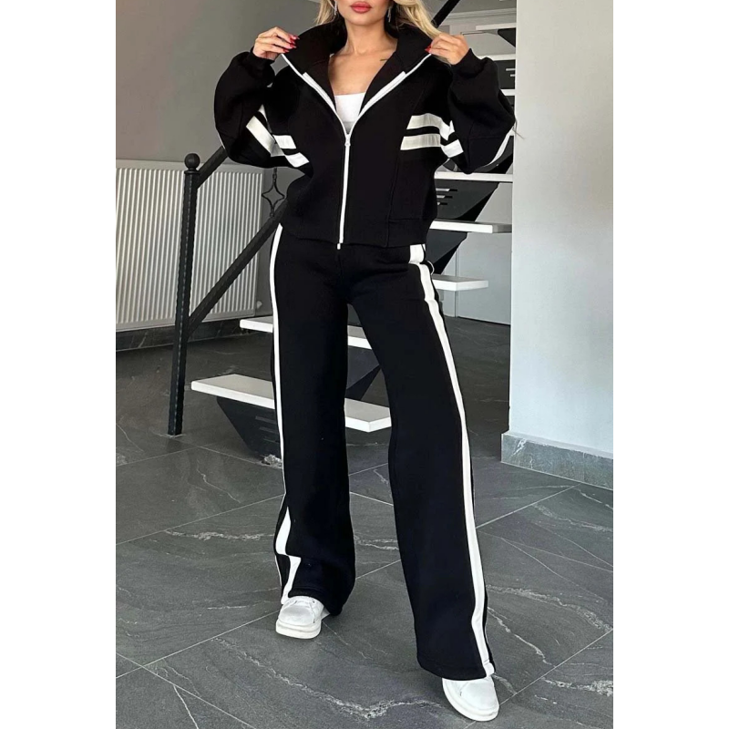 Model in the black set with white stripes, hands on the zipped jacket collar, full-length front view. 3