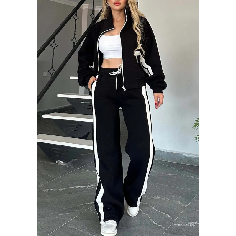 Black set with white stripes worn with the jacket open over a white crop top, one hand in pocket. 4