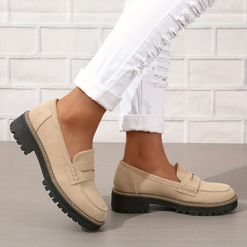 Beige suede-look loafers with chunky black soles, worn with rolled ripped white jeans, one foot lifted to show the side. 3