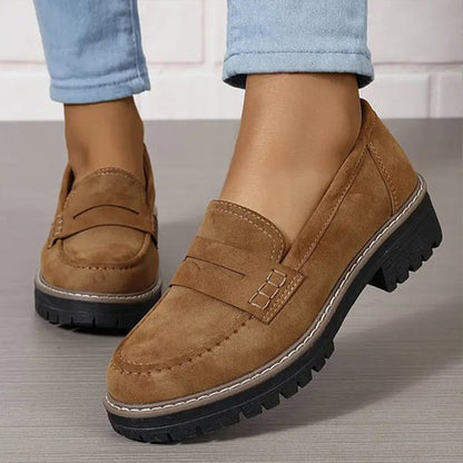 Tan suede-look loafers with contrast stitching and a chunky black sole, worn with light blue jeans, three-quarter view. 5