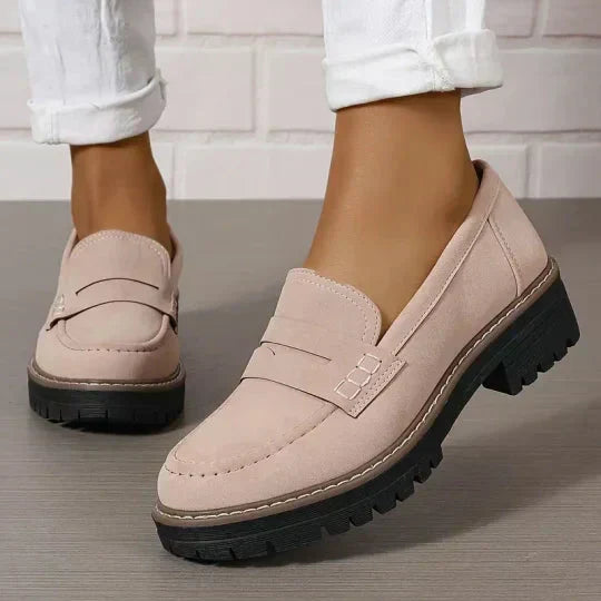 Soft pink-beige suede-look loafers with stitched penny strap and black chunky sole, worn with rolled white trousers. 8