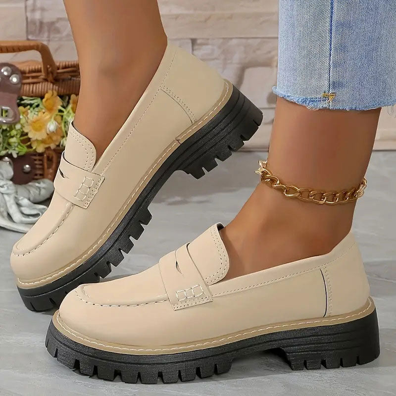 Cream smooth-finish loafers with a penny strap and thick black platform sole, worn with a gold chain anklet. 14