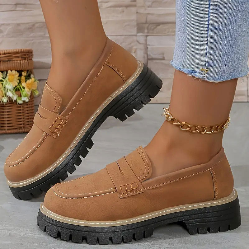 Tan suede-look loafers with orange stitching and a thick black platform sole, worn with a gold ankle chain. 17
