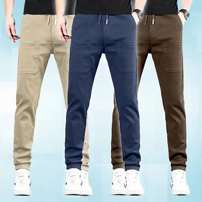 Three men in a row wearing drawstring trousers with front pockets, in beige, navy and brown 22