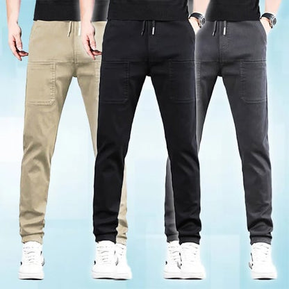 Three men side by side wearing the drawstring trousers in beige, black and dark grey 24