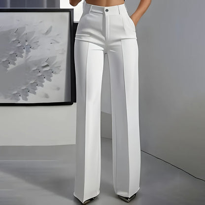 Front view of white high-waisted straight-leg trousers with pressed crease and button waist, worn by a model in a grey room. 3