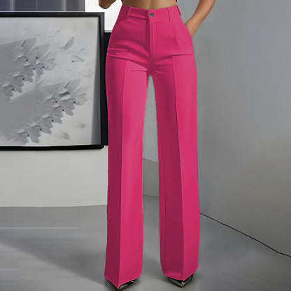 Front view of bright pink high-waisted straight-leg trousers with centre crease, worn by a model with one hand in a pocket. 7