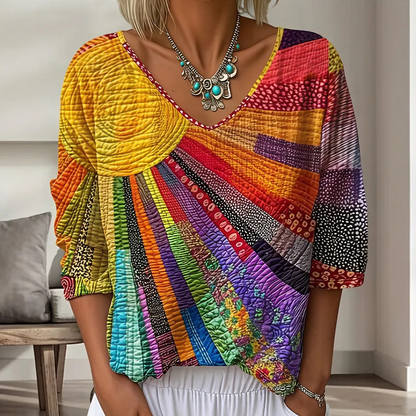 Close-up of the V-neck blouse in bright yellow, orange, red and purple patchwork with a sunburst design, worn with a turquoise necklace. 1