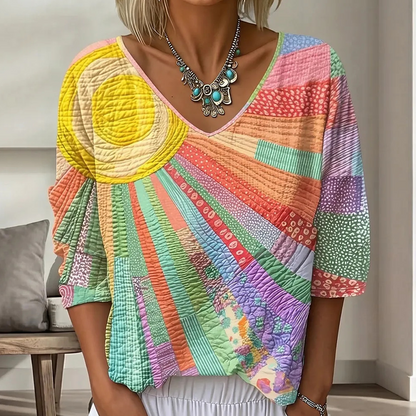 Close-up of the sunburst patchwork blouse in pastel colours with a bright yellow sun, radiating stripes and dotted panels on the sleeves. 6