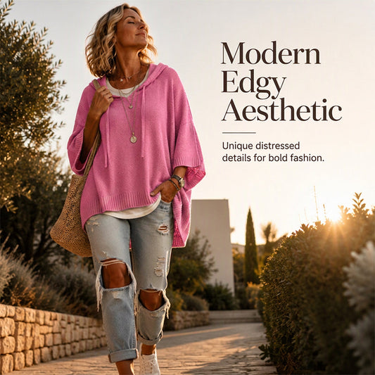 Woman in a pink oversized hooded jumper walking along a sunlit path, with a woven shoulder bag and ripped jeans. 2