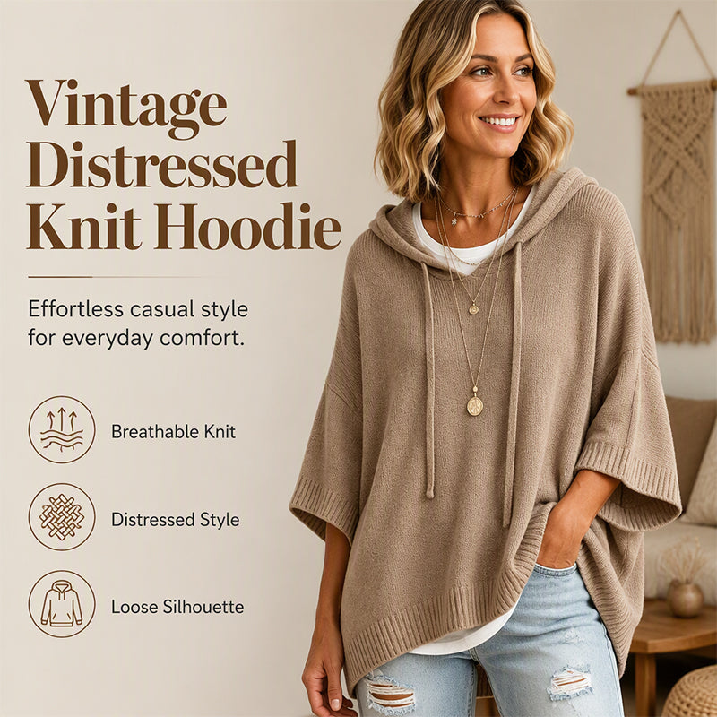 Smiling woman in a tan oversized hooded knit jumper with drawstrings and wide short sleeves, worn over a white top and ripped jeans. 1
