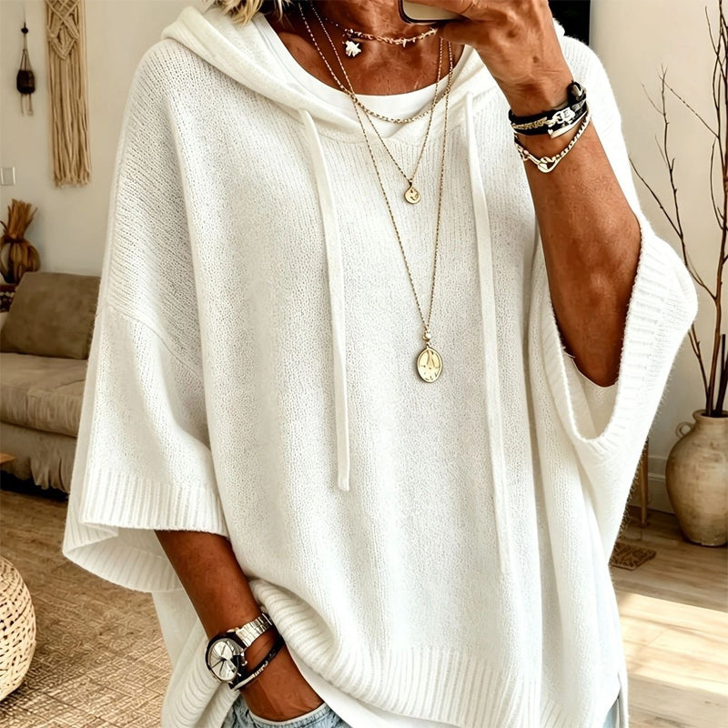 Torso view of the white hooded jumper with long drawstrings, ribbed trims and wide sleeves, worn with layered gold necklaces. 8