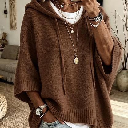 Torso view of the brown hooded jumper with drawstrings and ribbed hem, worn over a white top with gold necklaces. 18