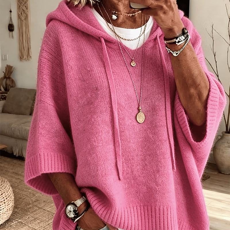 Torso view of the bright pink hooded jumper with a slightly fuzzy knit, drawstrings and ribbed trims, worn with necklaces. 16