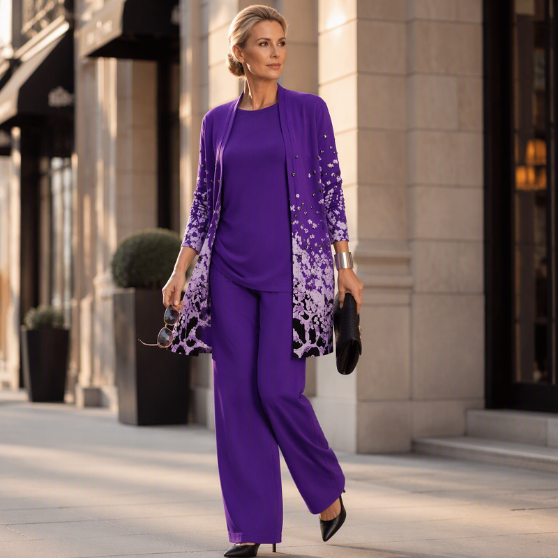 Model in the purple set walking along a city street, holding sunglasses and a black clutch, wearing black pointed heels. 12