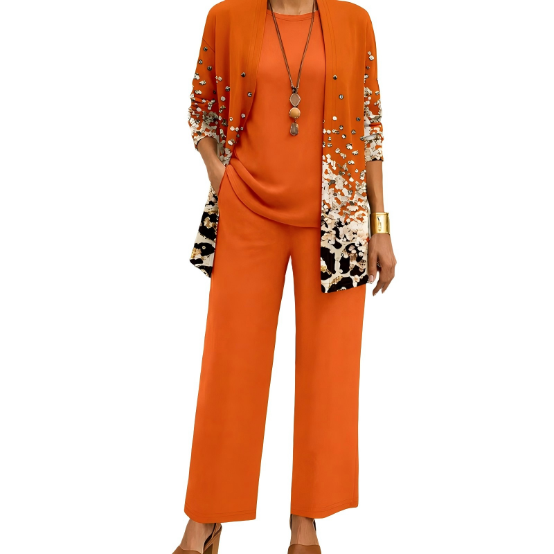 Model wearing the orange set, the open cardigan fading into a scattered speckled print towards the hem, with matching top and trousers. 3