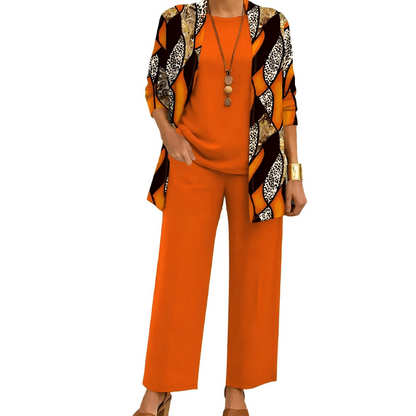 Model wearing the orange set, the open cardigan in a bold wavy panel print with leopard-spot details, over a plain top and trousers. 9